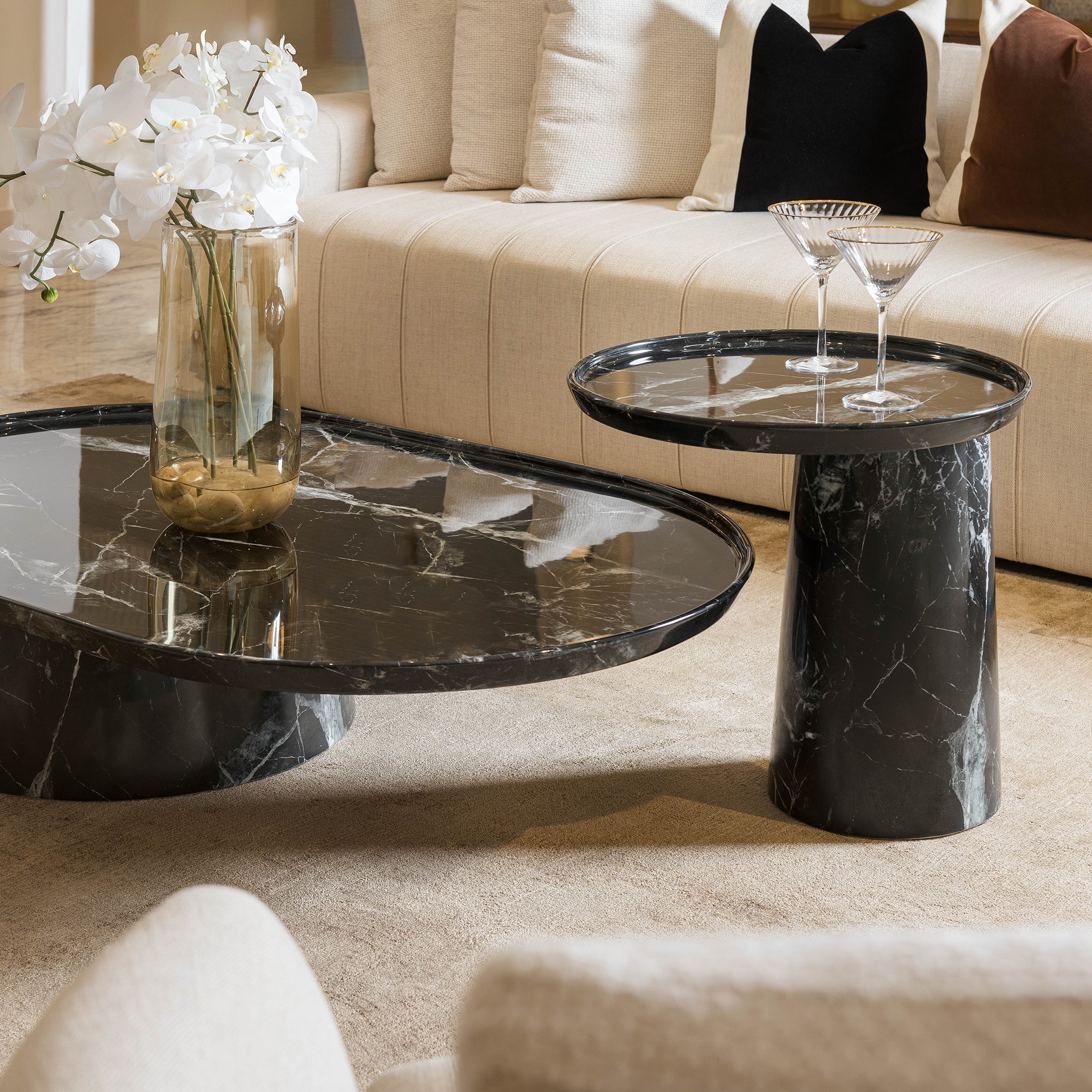 Modern living room with marble coffee table and side table, featuring a vase of white flowers.
