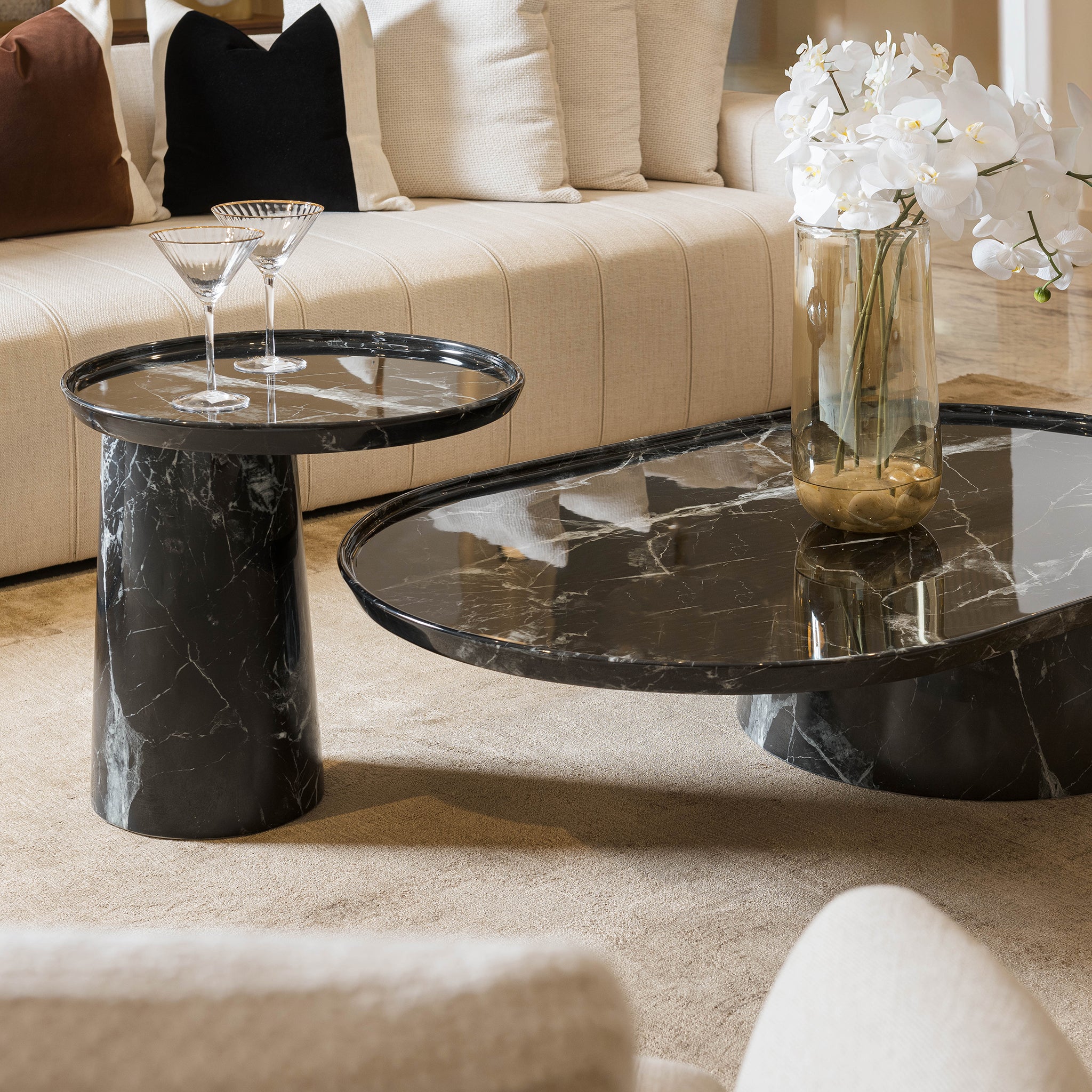 Modern living room with marble coffee table and side table, featuring a vase of white flowers.